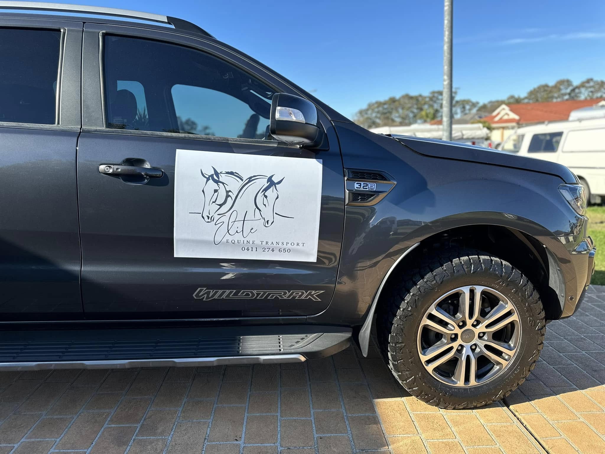 Dark grey Wildtrak ute with a horse-head logo sign on the front door