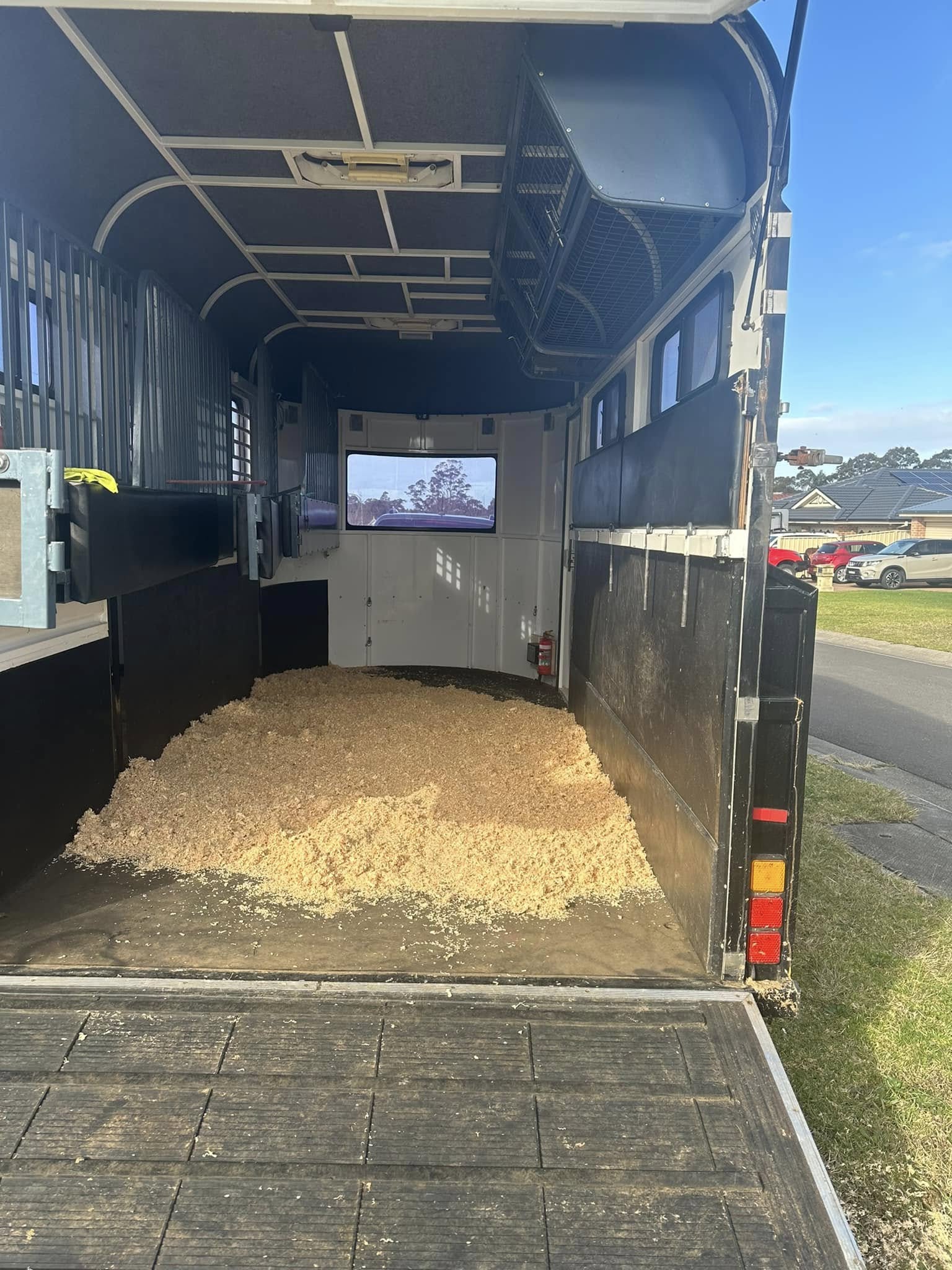 Open rear ramp of a horse float with a bed of wood shavings inside